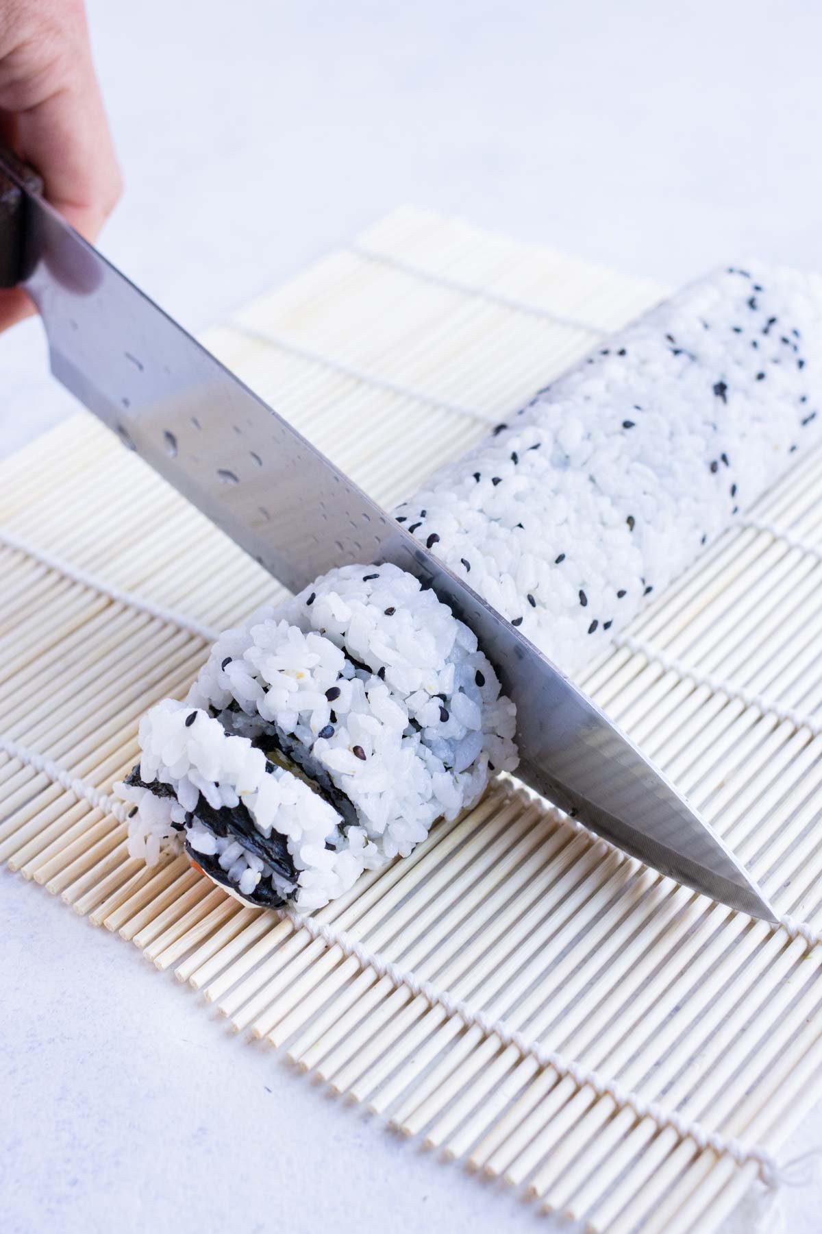 Sushi roll is cut with a wet knife.