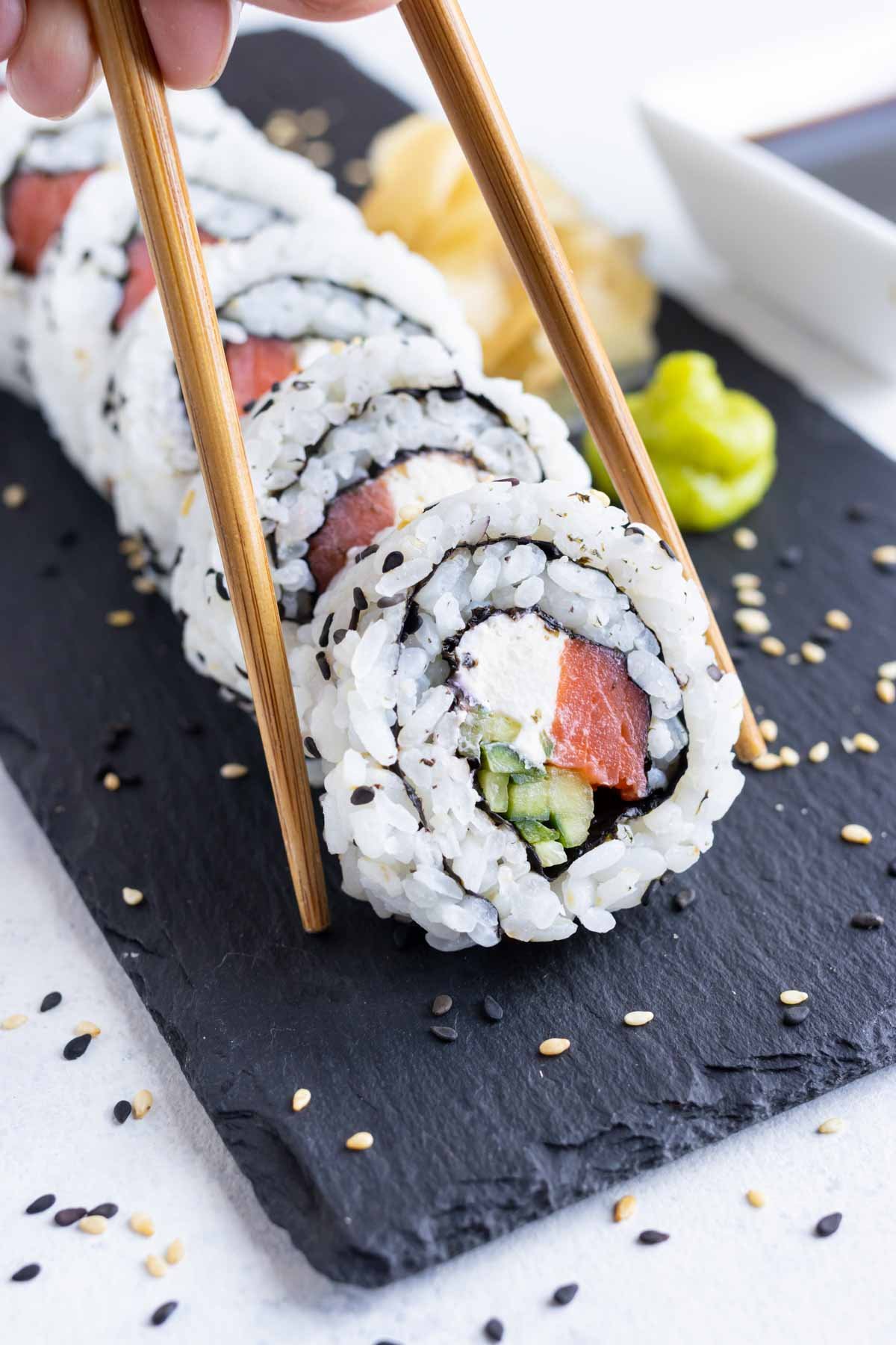 Homemade sushi is picked up with chopsticks.