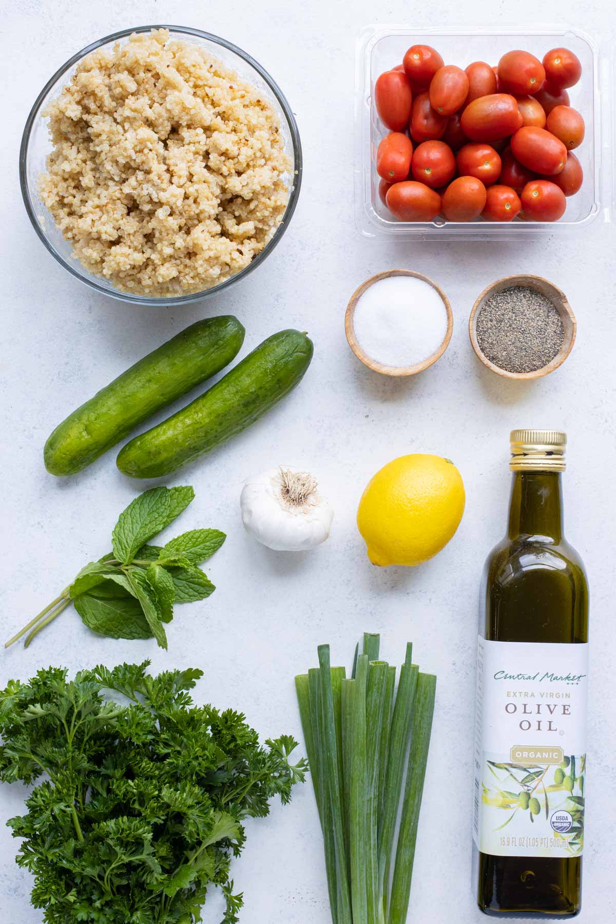 Quinoa, tomatoes, mint, cucumbers, green onions, parsley, lemon, garlic, and oil are the ingredients for this simple salad.