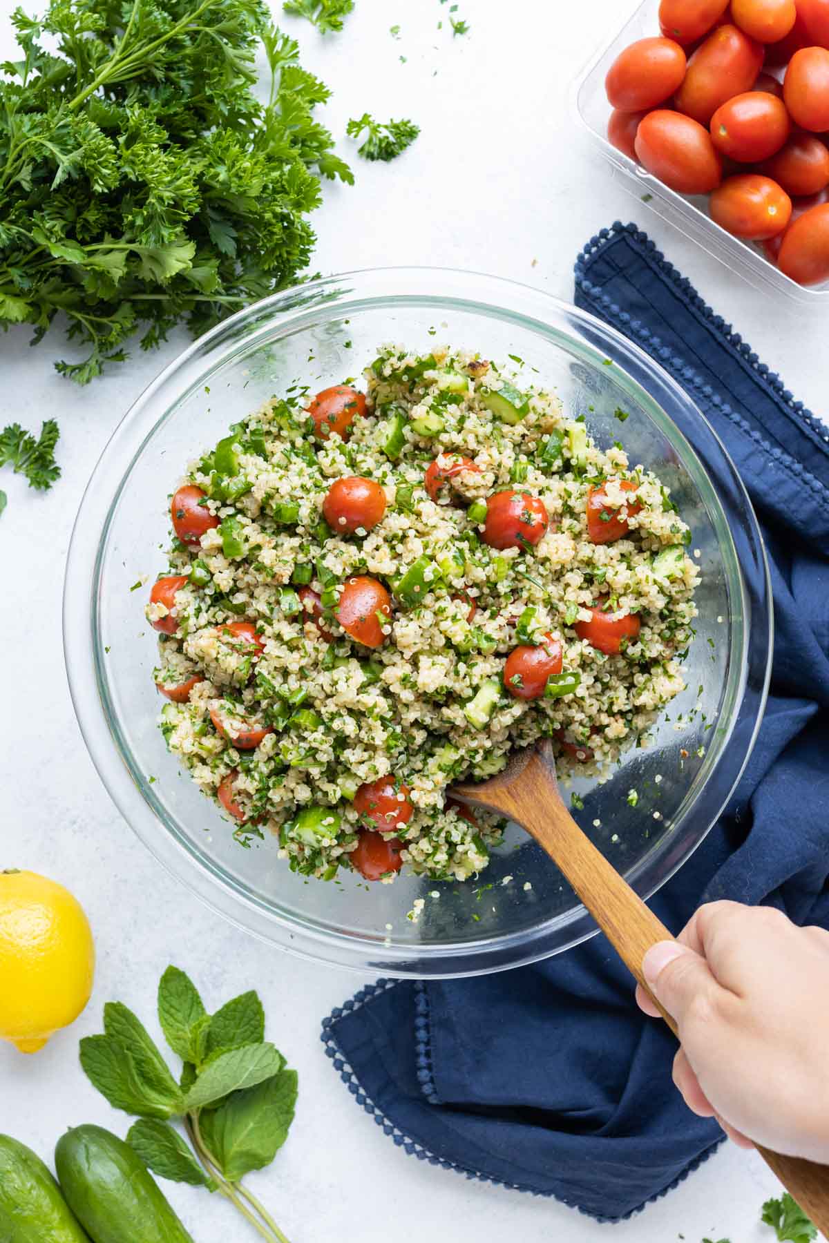 A hand is shown dishing a serving of quinoa tabbouleh