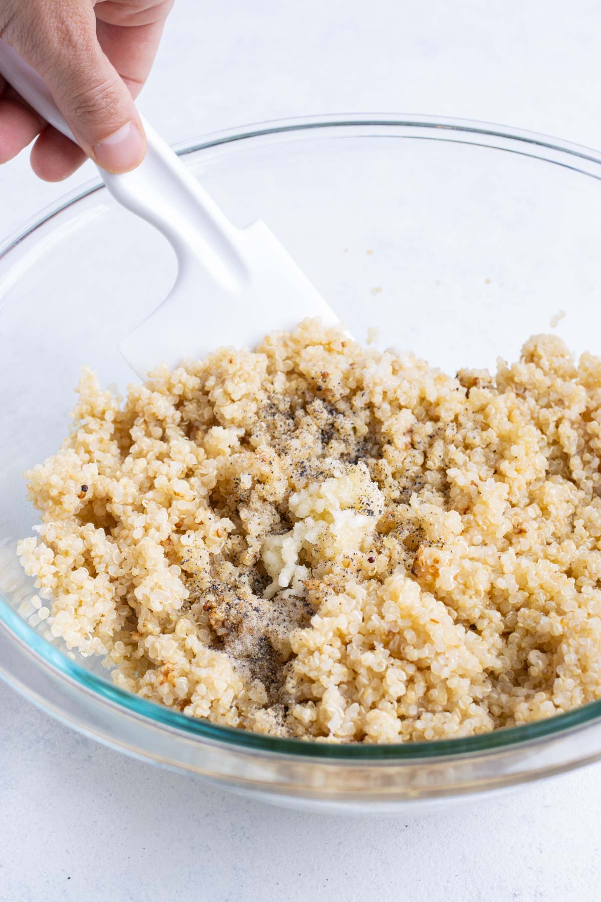 Quinoa is mixed with salt, pepper, garlic, oil, and lemon juice.