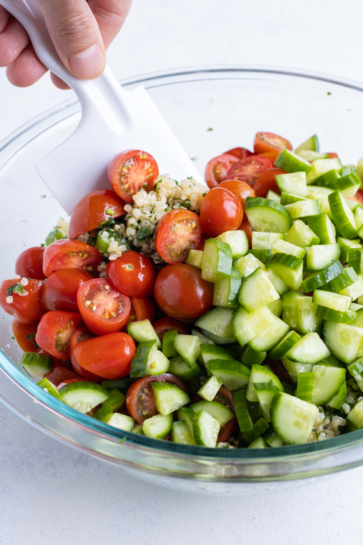 Tomatoes and cucumbers are added to the quinoa salad.