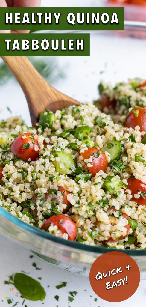 Quinoa Tabbouleh is served from a glass bowl with a wood spoon.