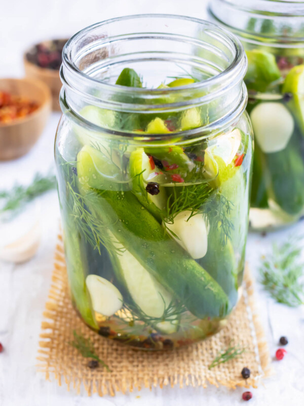 Refrigerator pickles in a glass jar with dill sprigs, red pepper flakes, and garlic cloves.