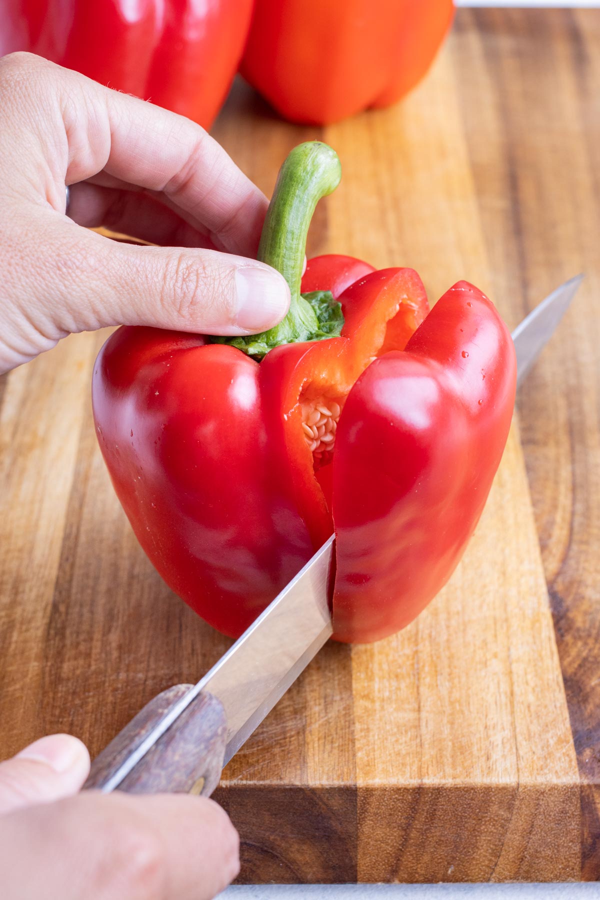 A shark knife slices the outside of a bell pepper.