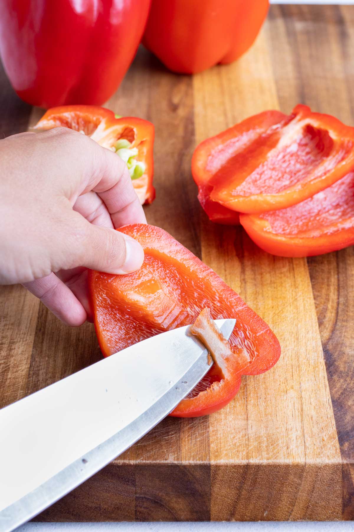 A knife removes the membrane and seeds of a pepper.