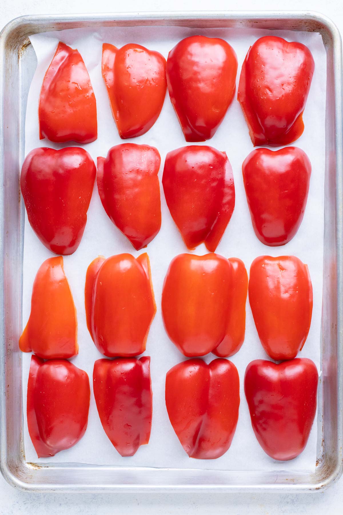 A sheet pan with even rows of sliced bell peppers.