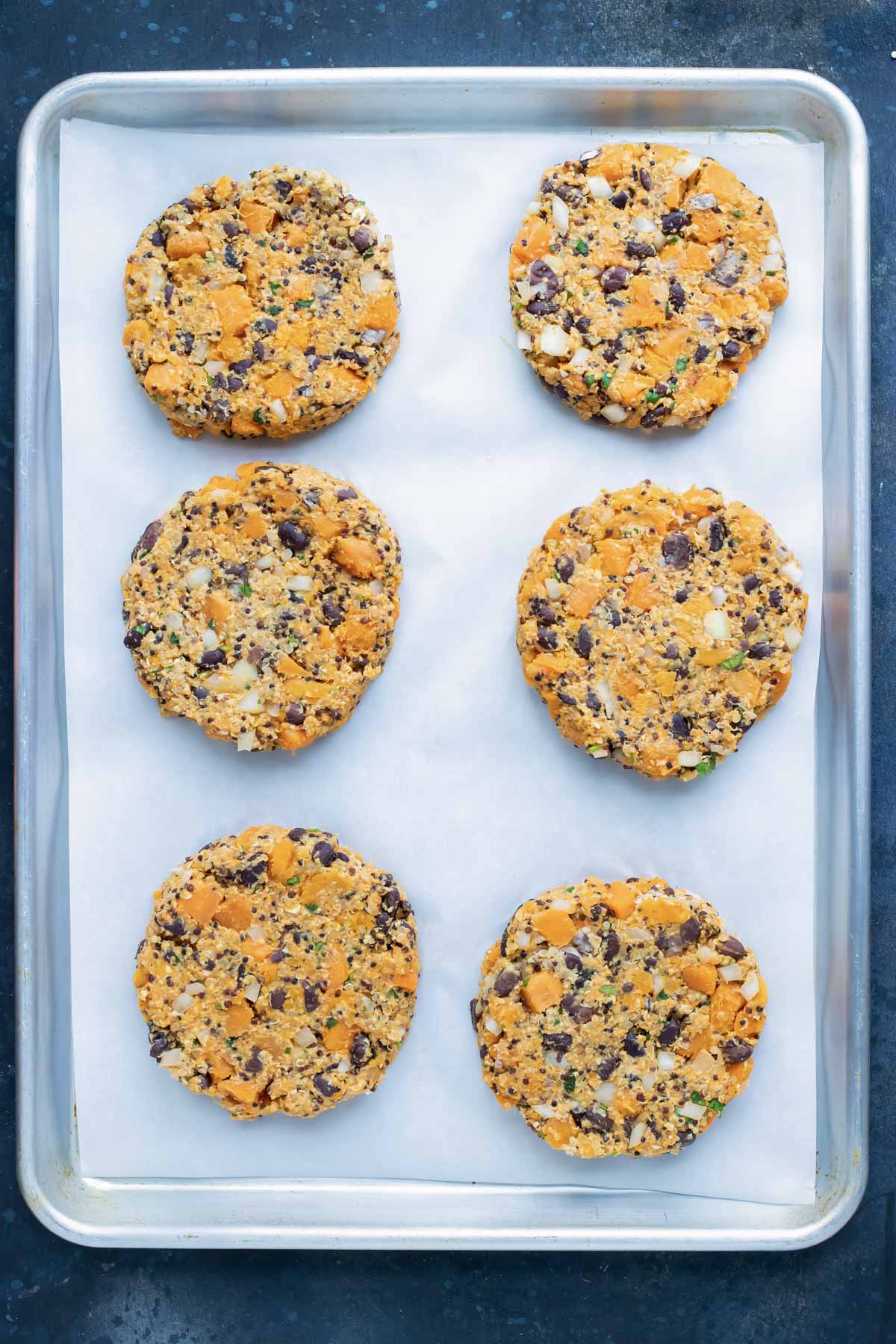 Sweet Potato Black Bean Burger patties on a lined sheet pan.