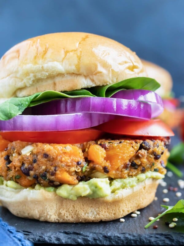 Sweet potato black bean veggie burger patty on a gluten-free bun with red onion, tomatoes, and lettuce.