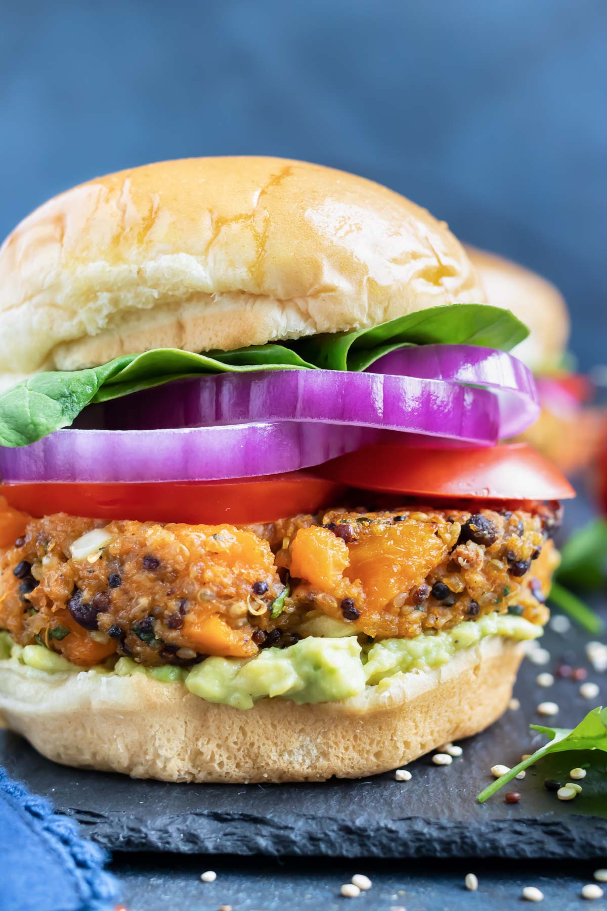 Sweet potato black bean veggie burger patty on a gluten-free bun with red onion, tomatoes, and lettuce.