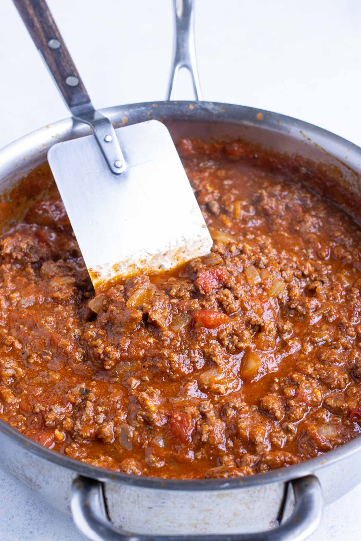 A skillet full of tomato meat sauce simmers.