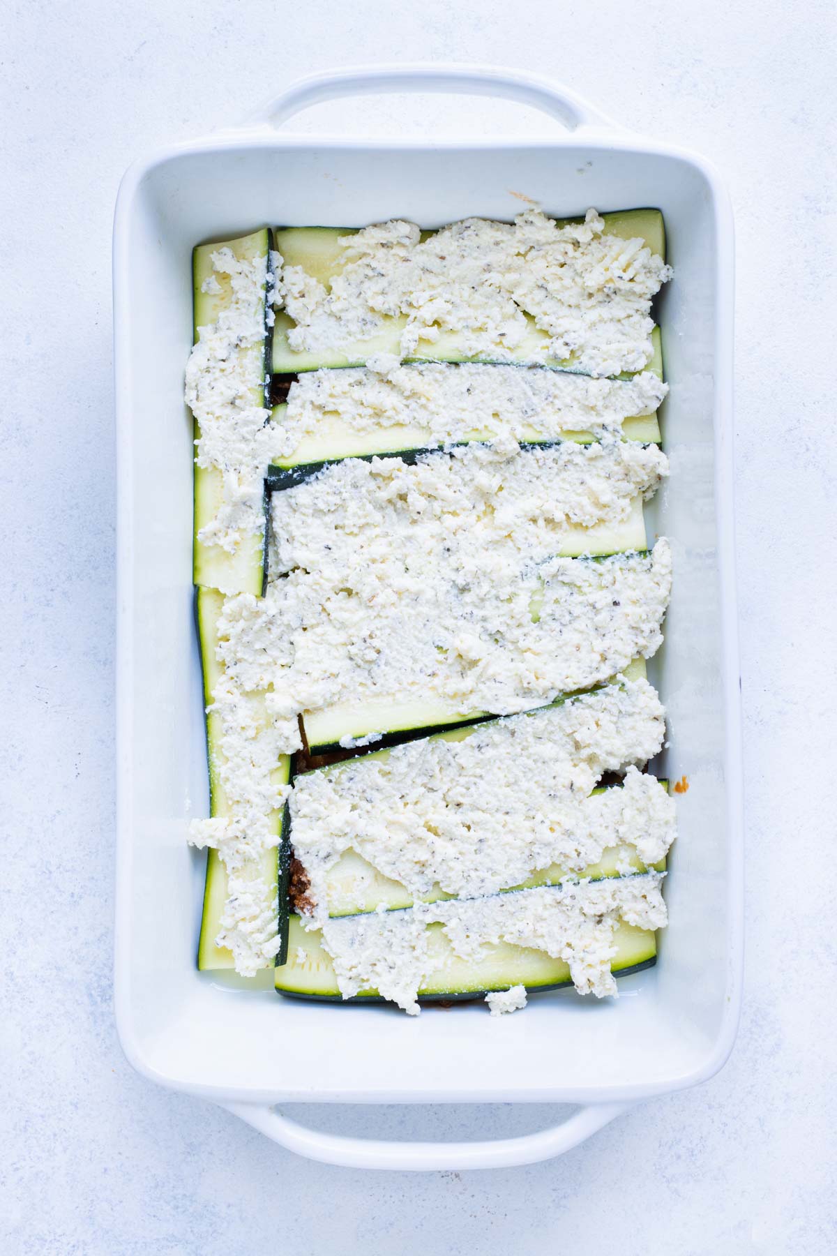 The healthy zucchini lasagna is formed by layering sauce, zucchini, and cheese mixture.