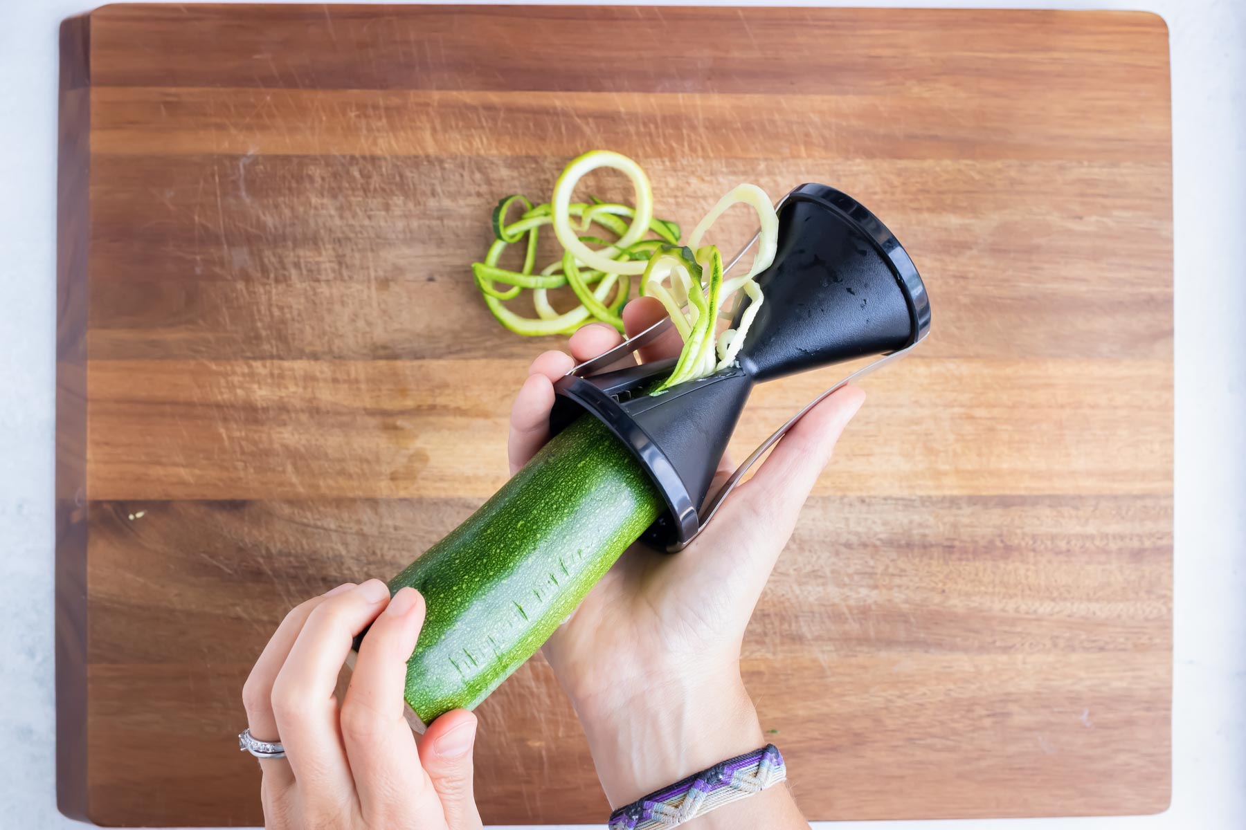 How to use a handheld veggie spiralizer to make zucchini noodles.