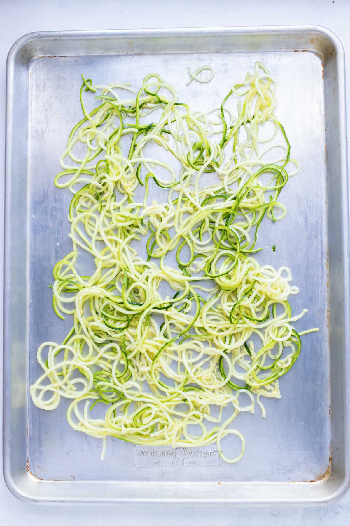 Sprialized zucchini noodles on a baking sheet.
