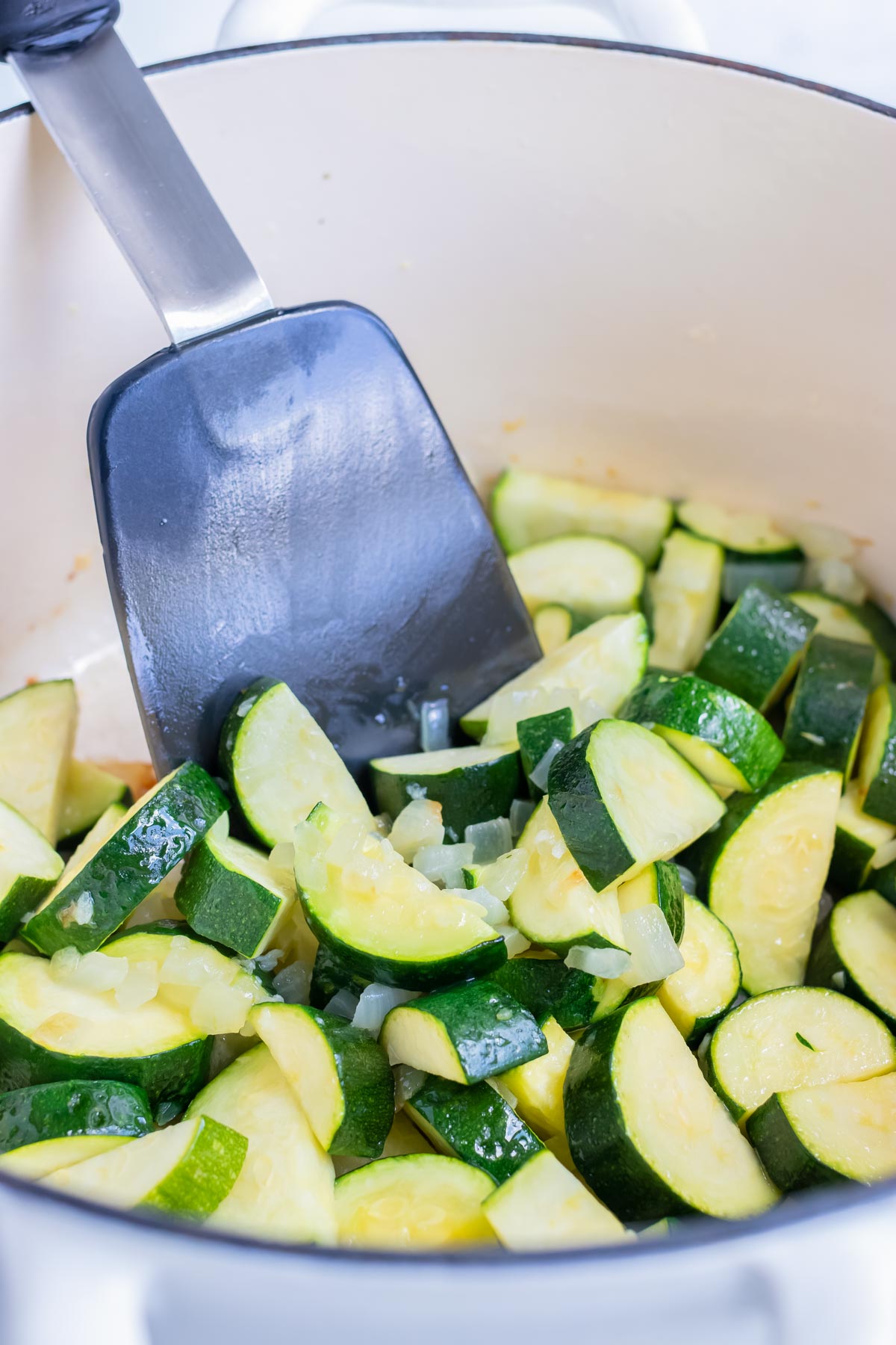 Zucchini slices are sautéed on the stove.