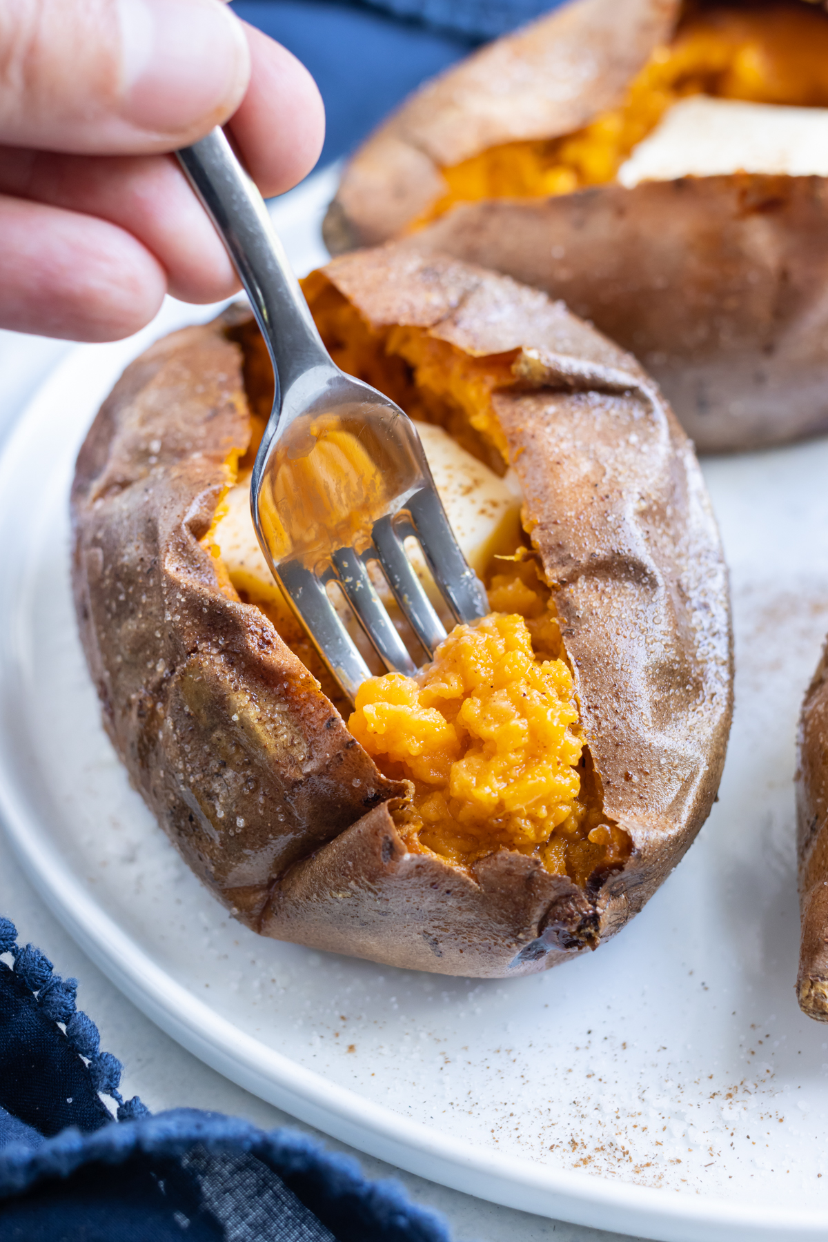 A fork digs into an air fried baked sweet potato.