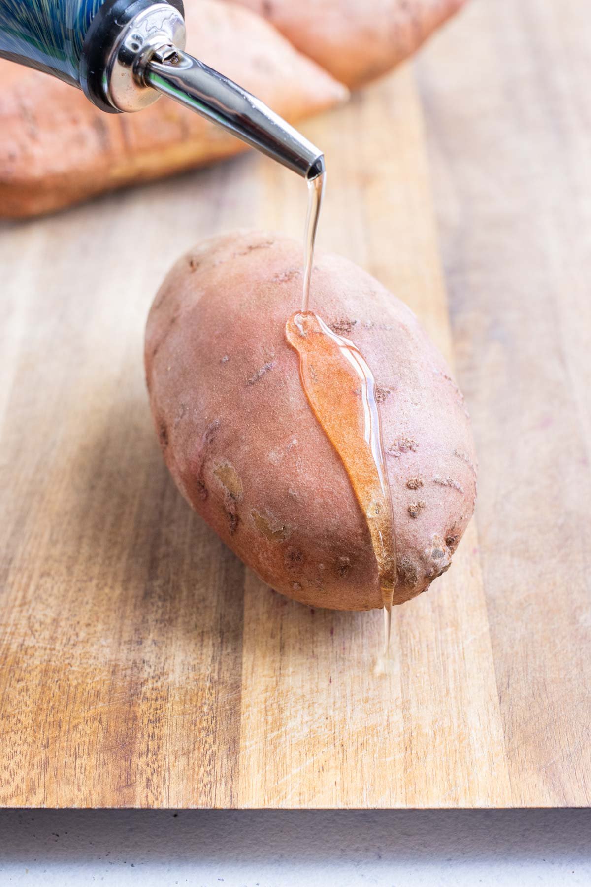 Oil is drizzled over a sweet potato.
