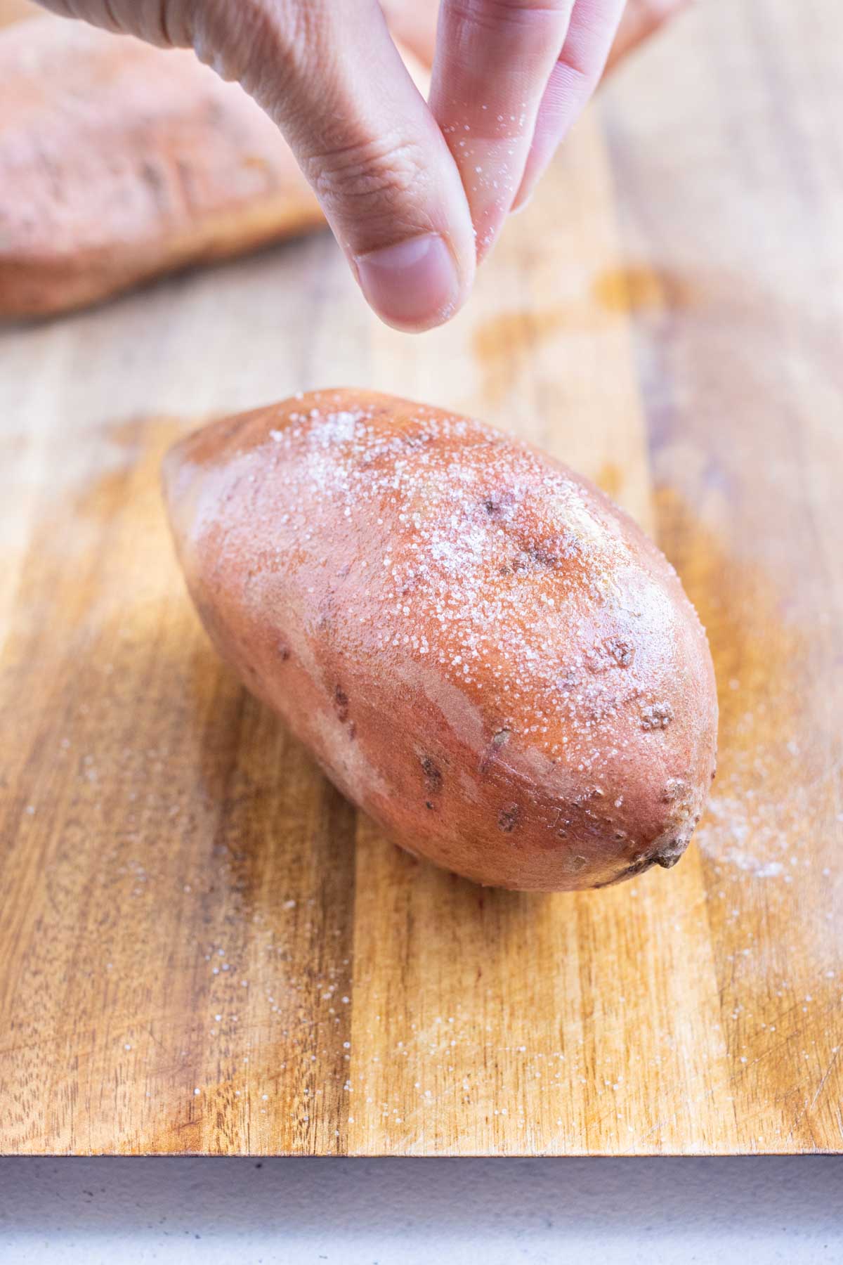 Salt is sprinkled on the outside of a sweet potato.