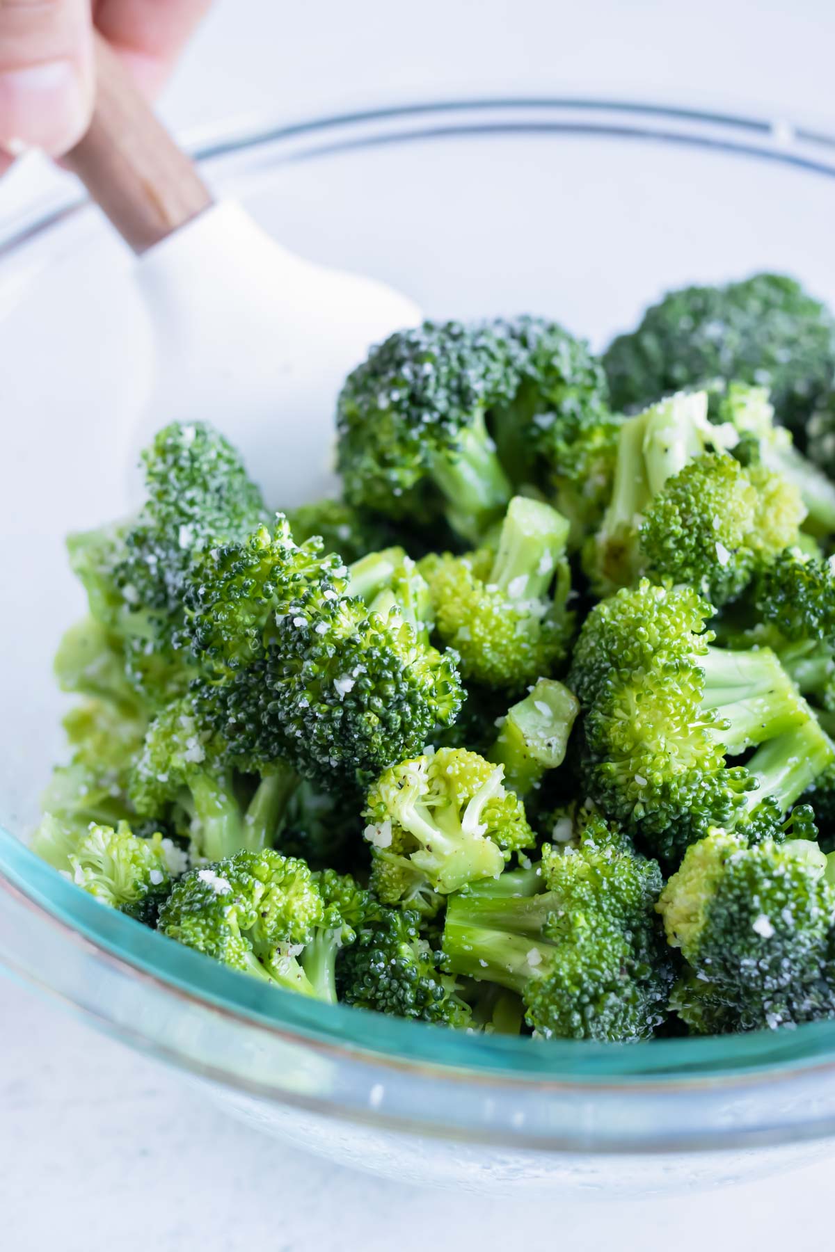 Broccoli florets are covered in an oil, garlic, and Parmesan cheese mixture ready to be roasted in the air fryer.