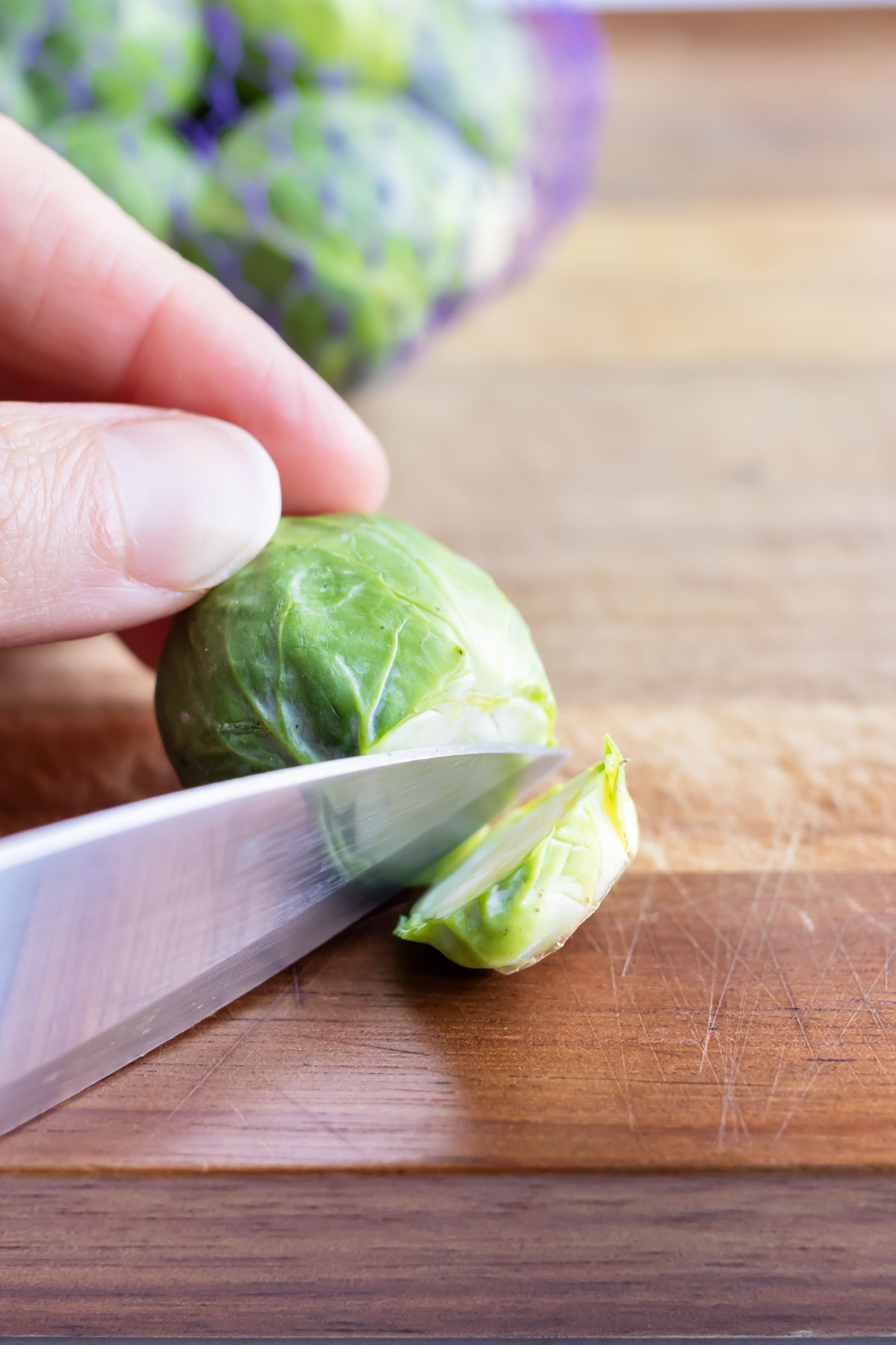 A brussel sprout is chopped and prepared for cooking.