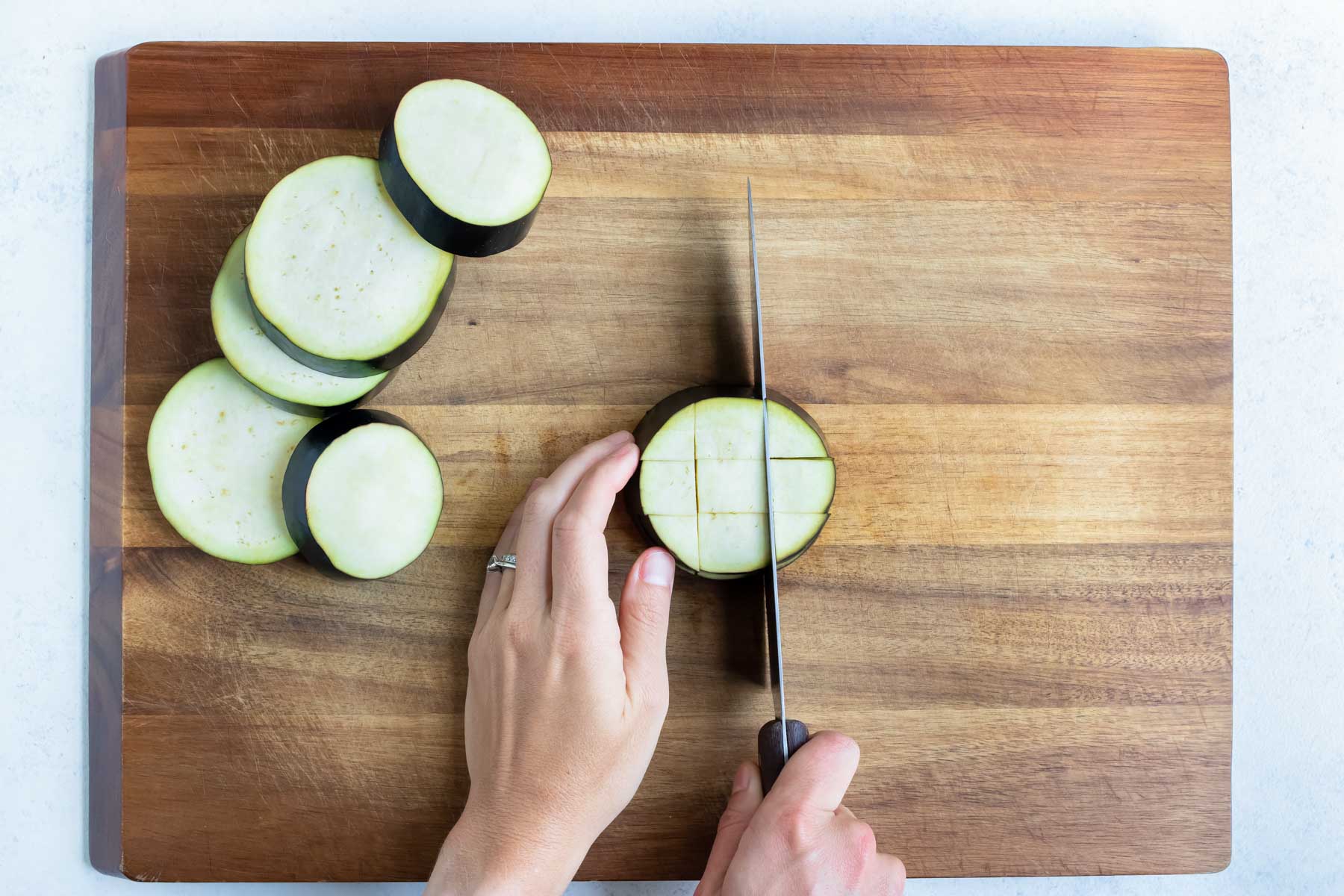 The eggplant is cubed on a cutting board.