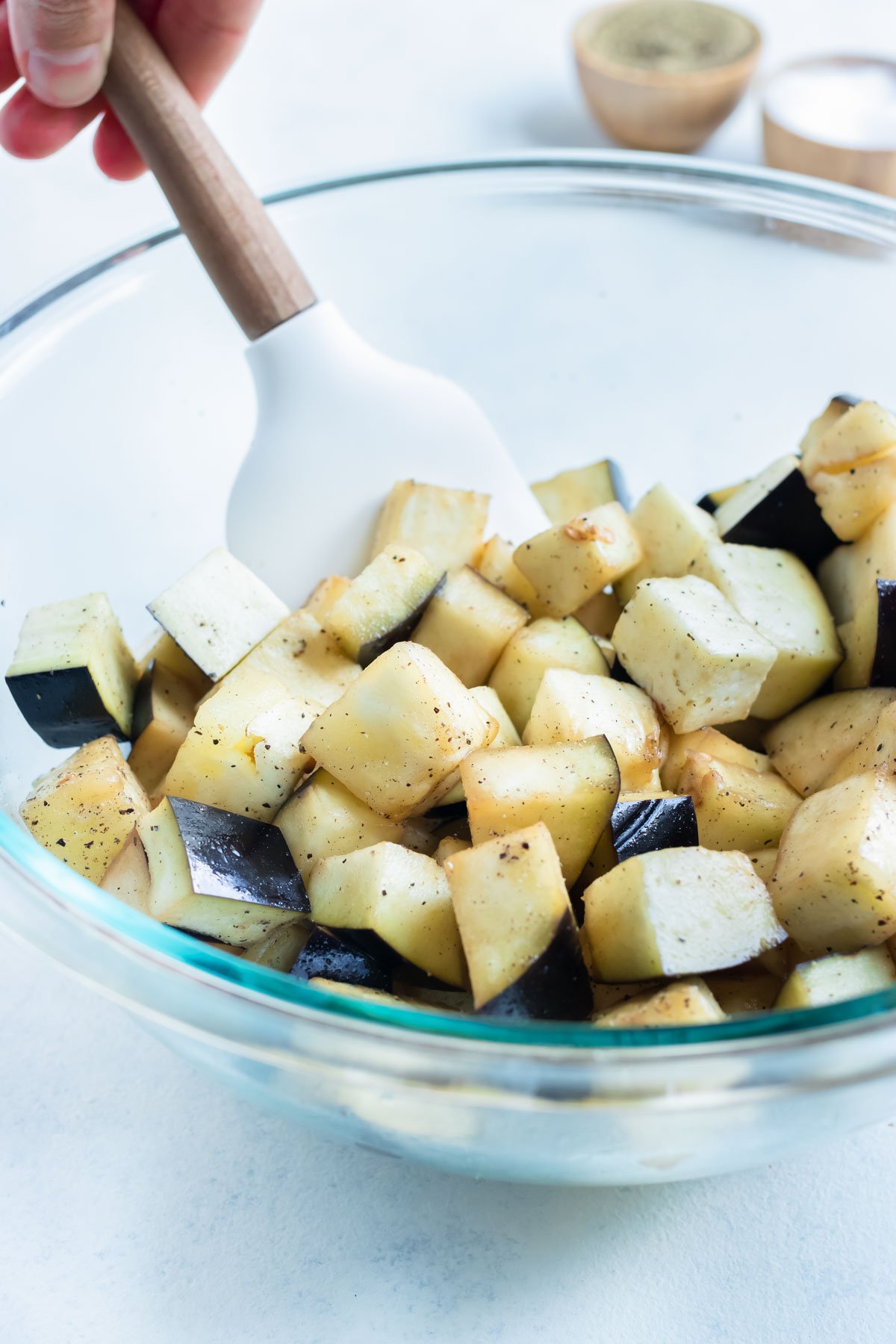 Cubed eggplant is covered in oil in a bowl.