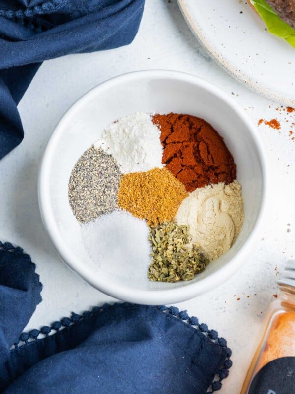 Paprika, garlic powder, onion powder, salt, and black pepper are in a mixing bowl for a homemade burger seasoning recipe.