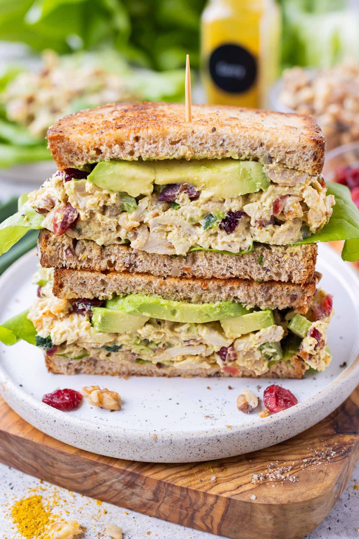 A curry chicken salad sandwich with cranberries is cut in half and stacked.