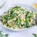 A white bowl full of pesto pasta salad is placed on the counter