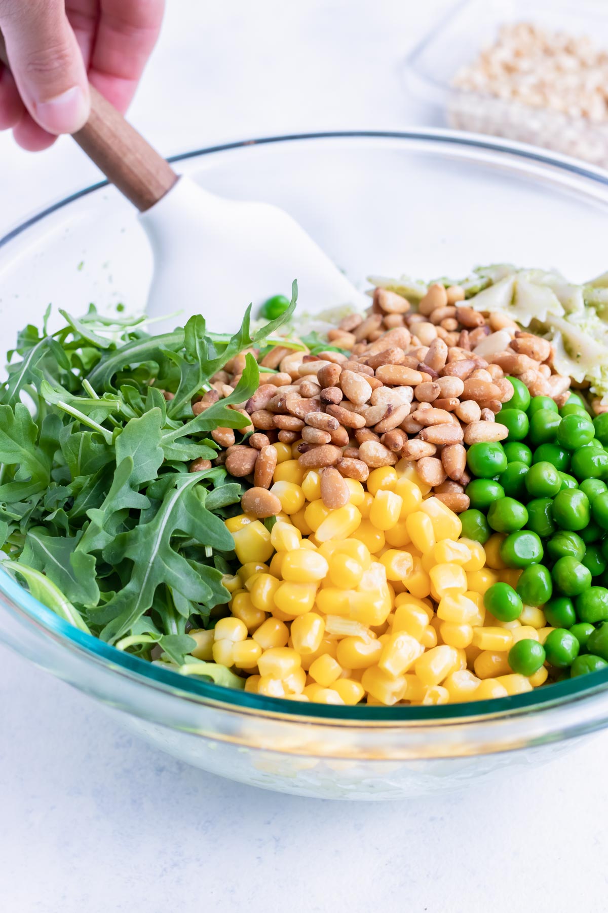 All the ingredients for this pesto pasta salad are added to a glass bowl.