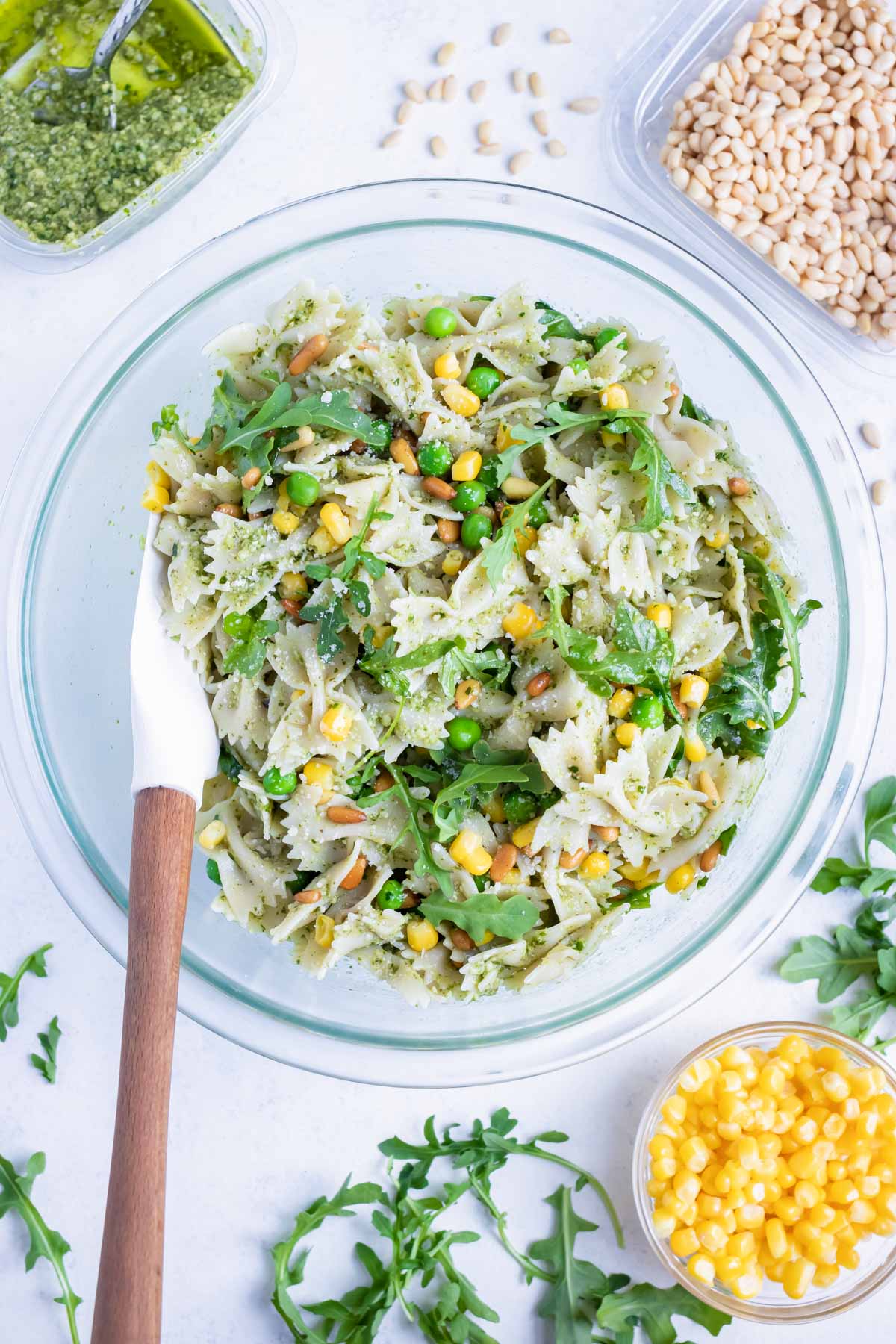 All of the pesto pasta salad ingredients are mixed together in a bowl.