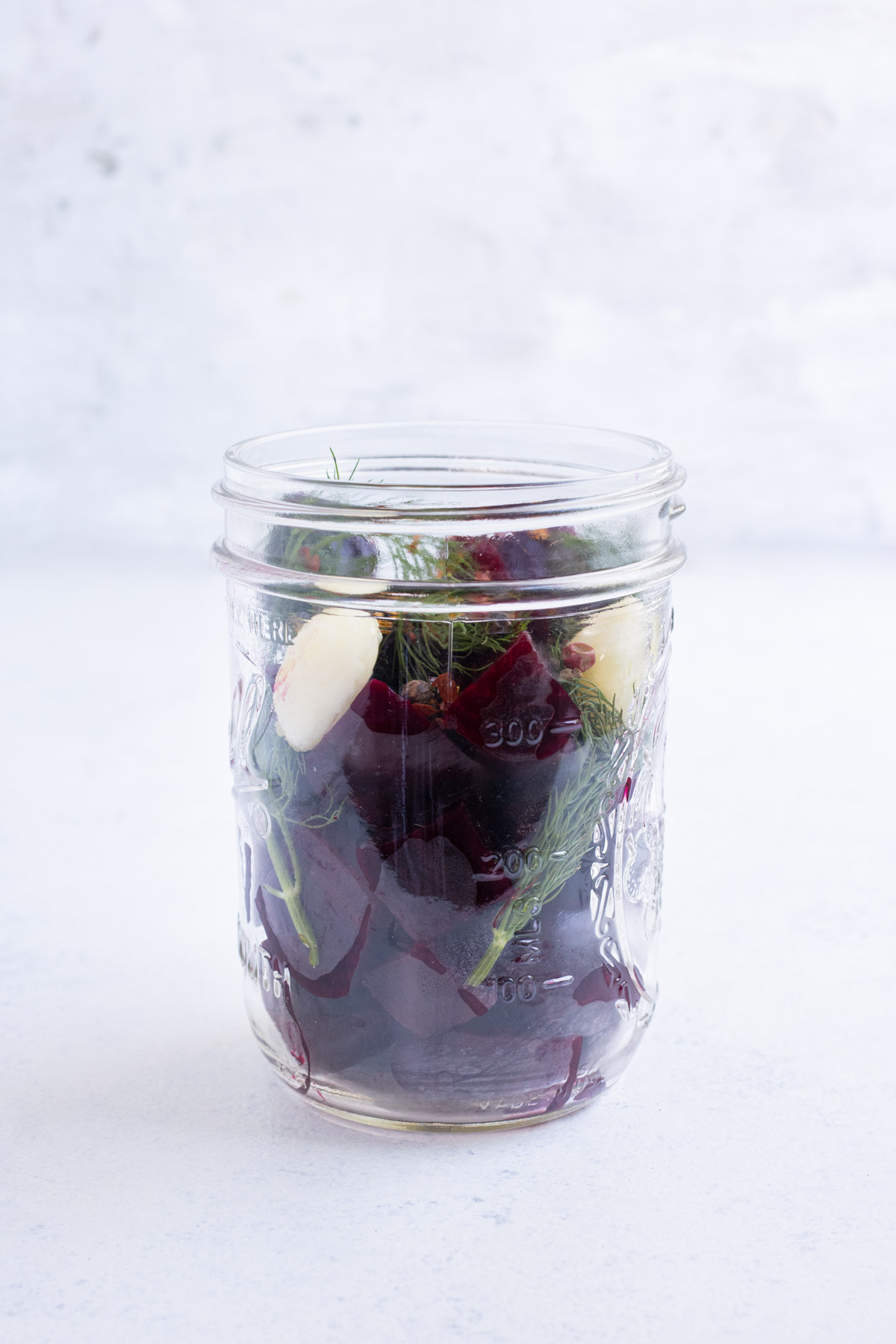 Roasted beets in a jar with garlic, dill, and pepper.