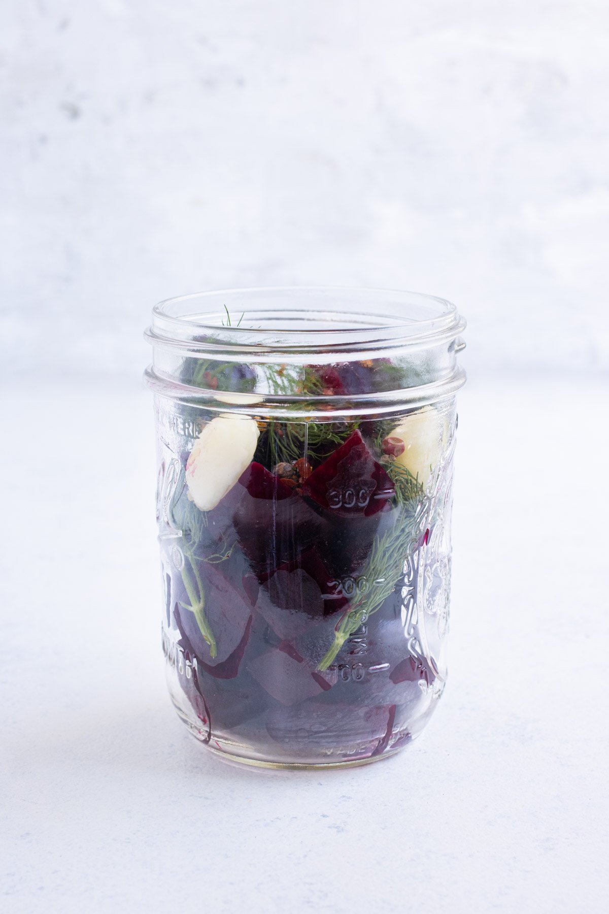 Roasted beets in a jar with garlic, dill, and pepper.