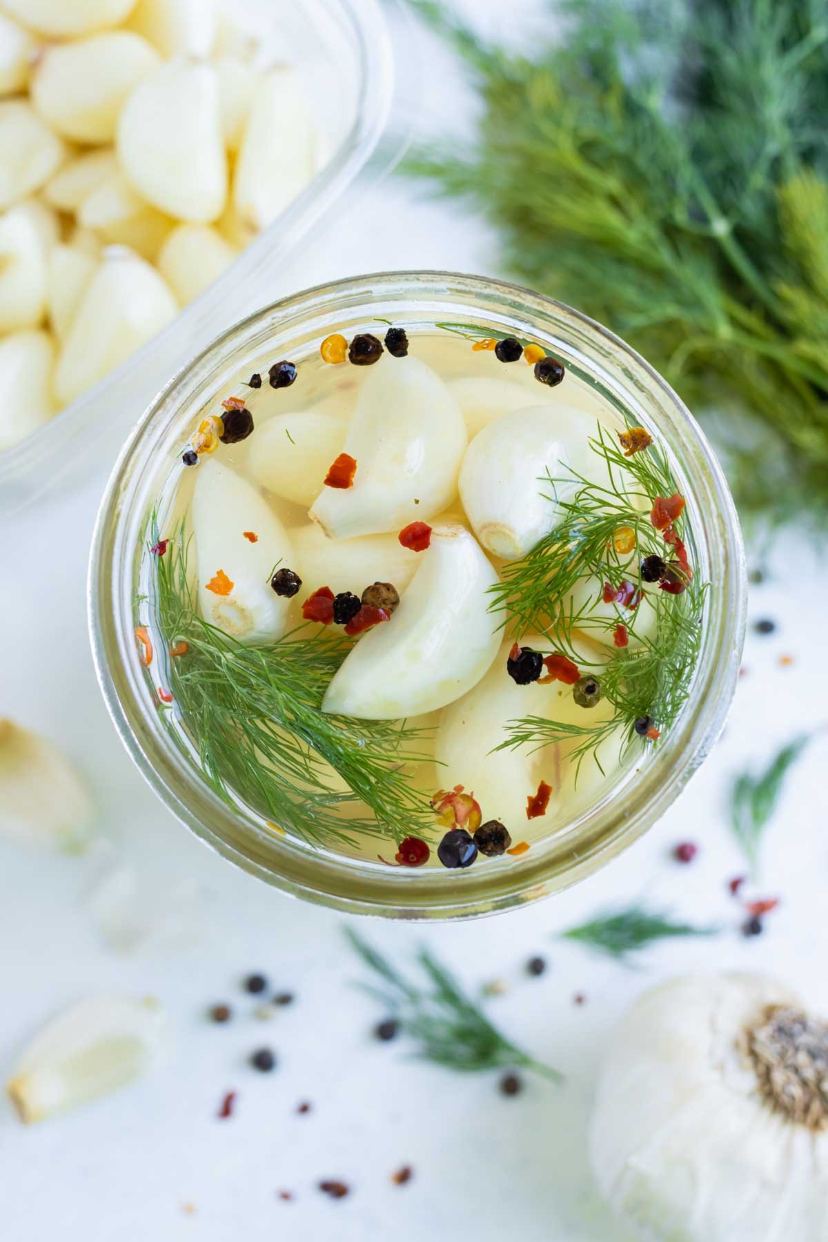 An overhead shot of pickled garlic in a jar.