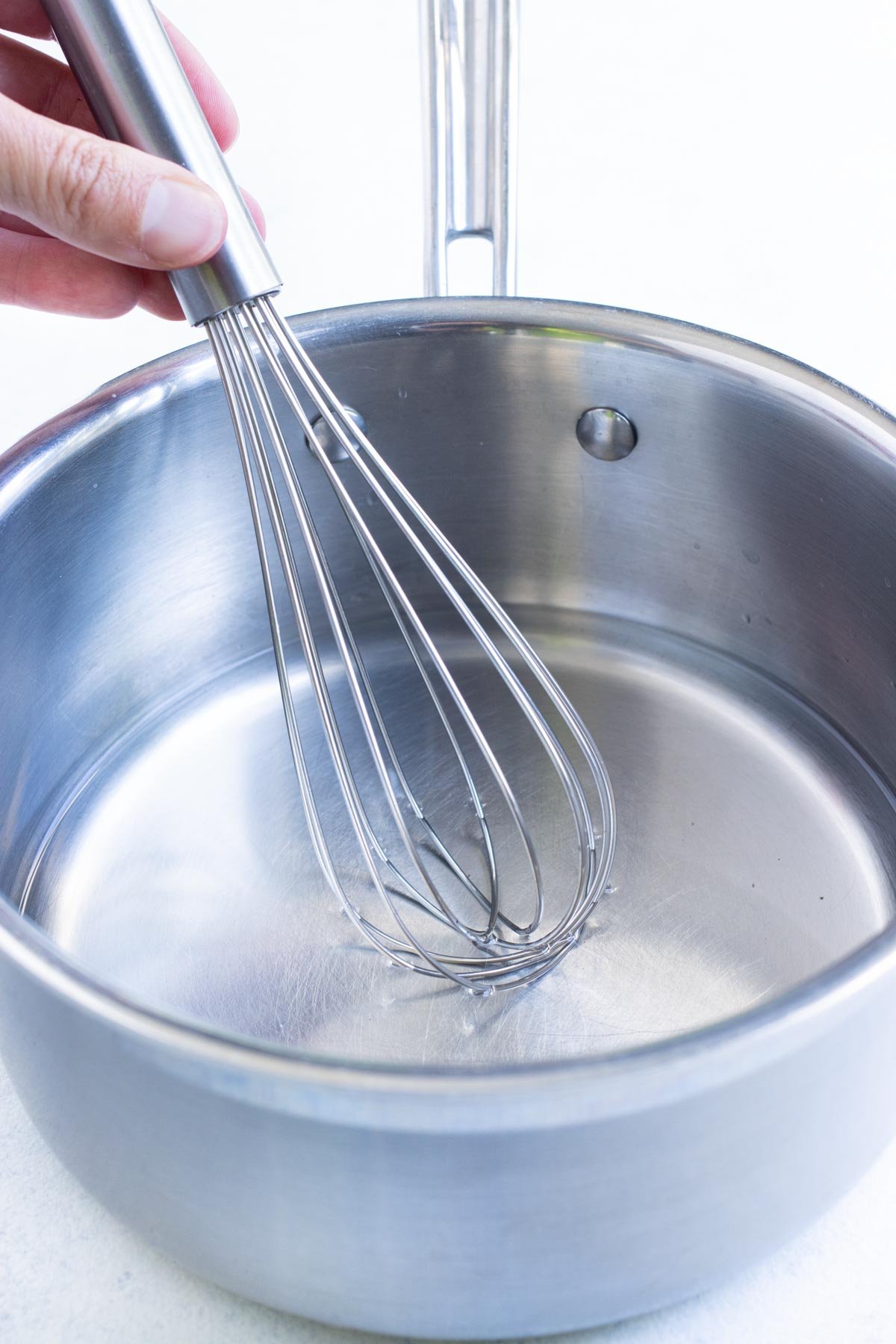 A whisk is used to mix pickling brine.