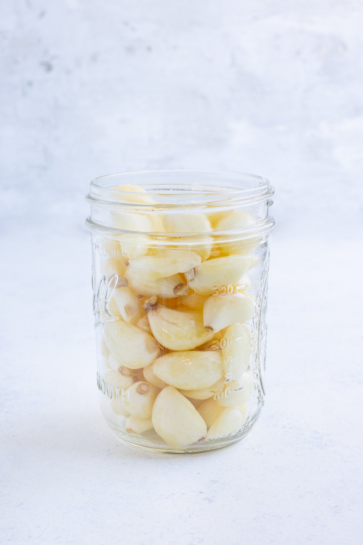 A mason jar is full of peeled garlic cloves.