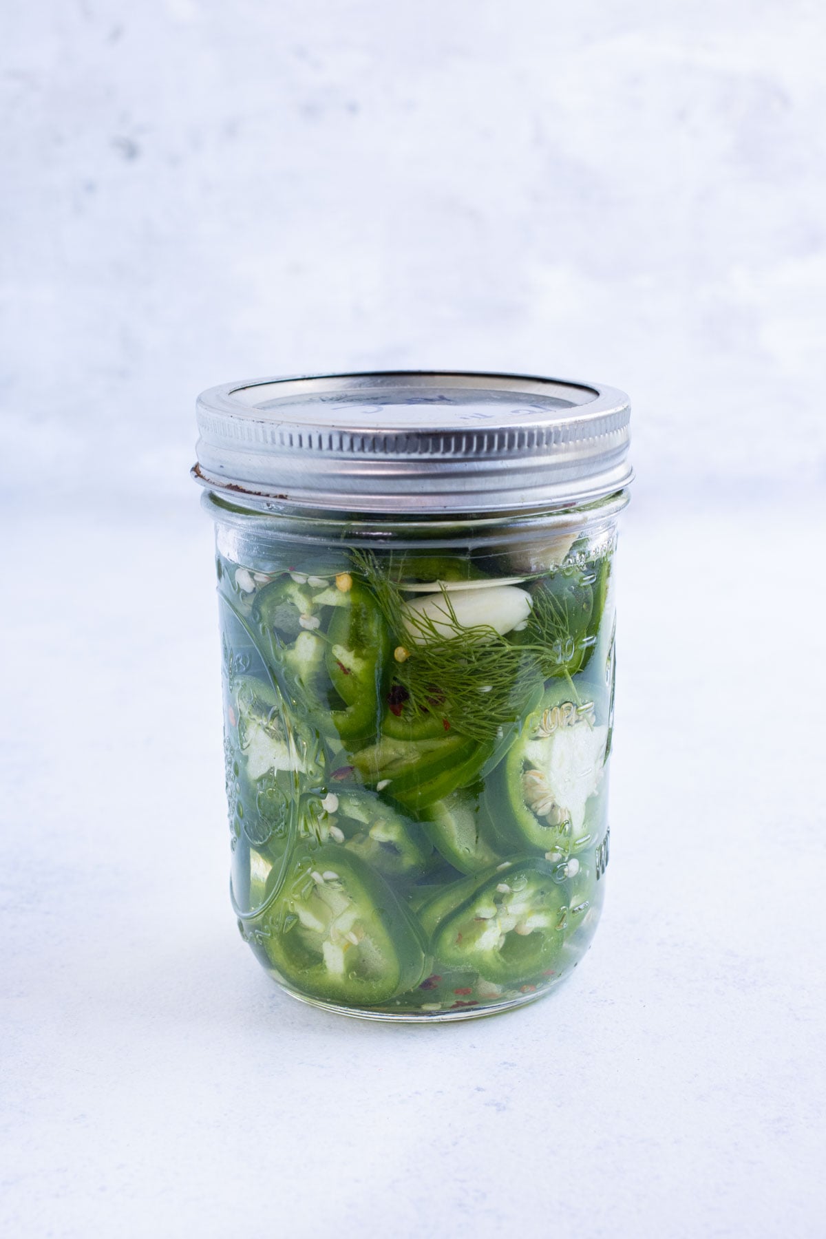The lid is placed on a jar of pickled jalapeños.