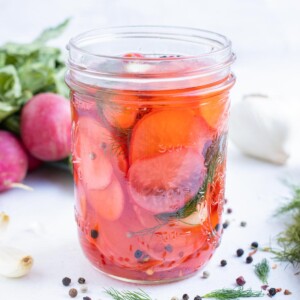 Pickle radishes in a jar with garlic, dill, and pepper.