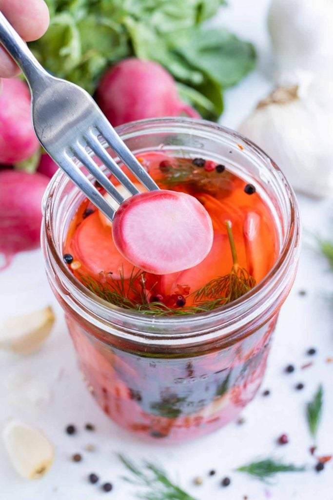 A fork scoops out a pickled radish.