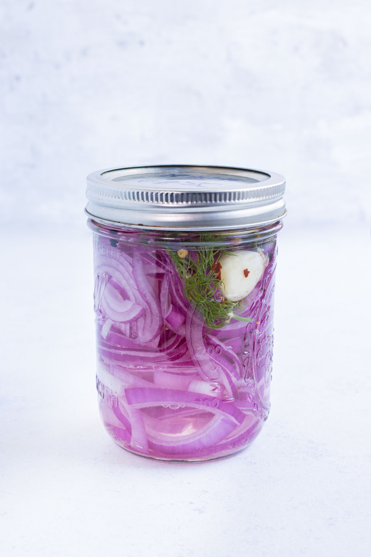 A lid is tightly sealed on a jar with pickled onions.