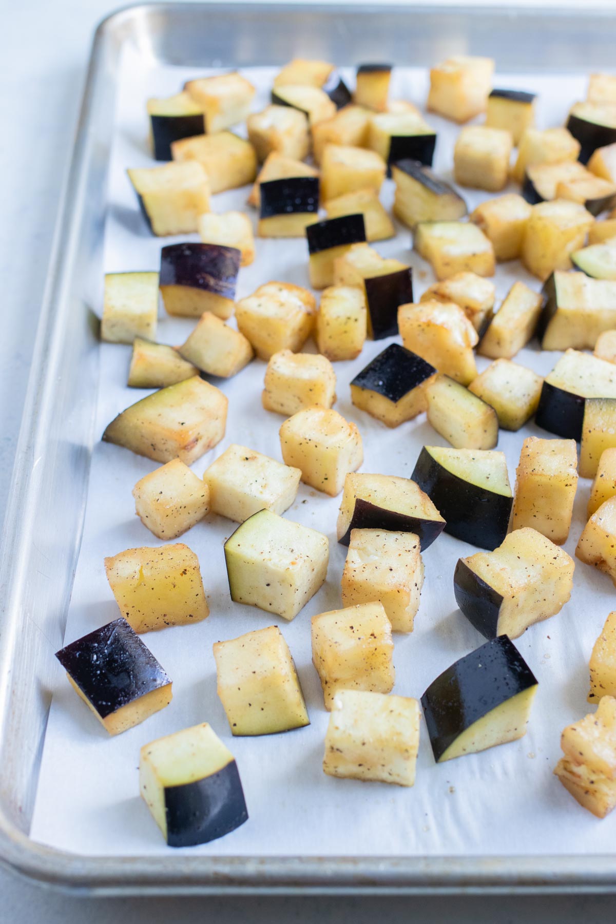 Eggplant cubes are laid flat on a baking sheet.