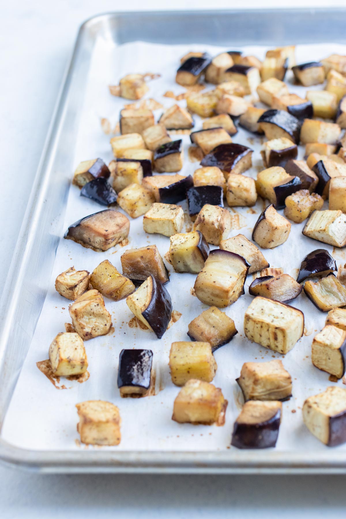 The eggplant is roasted in the oven on a baking sheet.