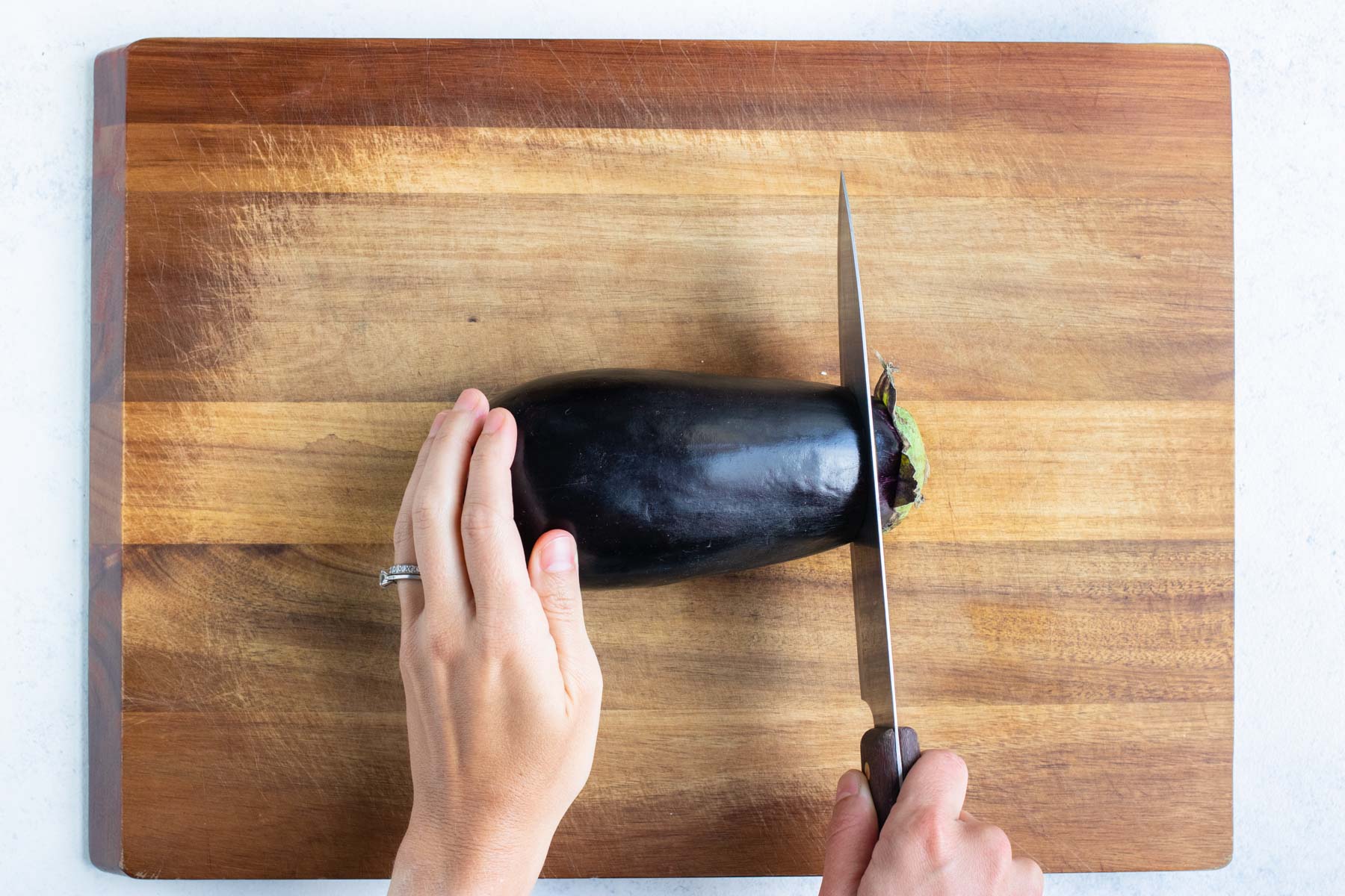 The top of the eggplant is removed with a knife.