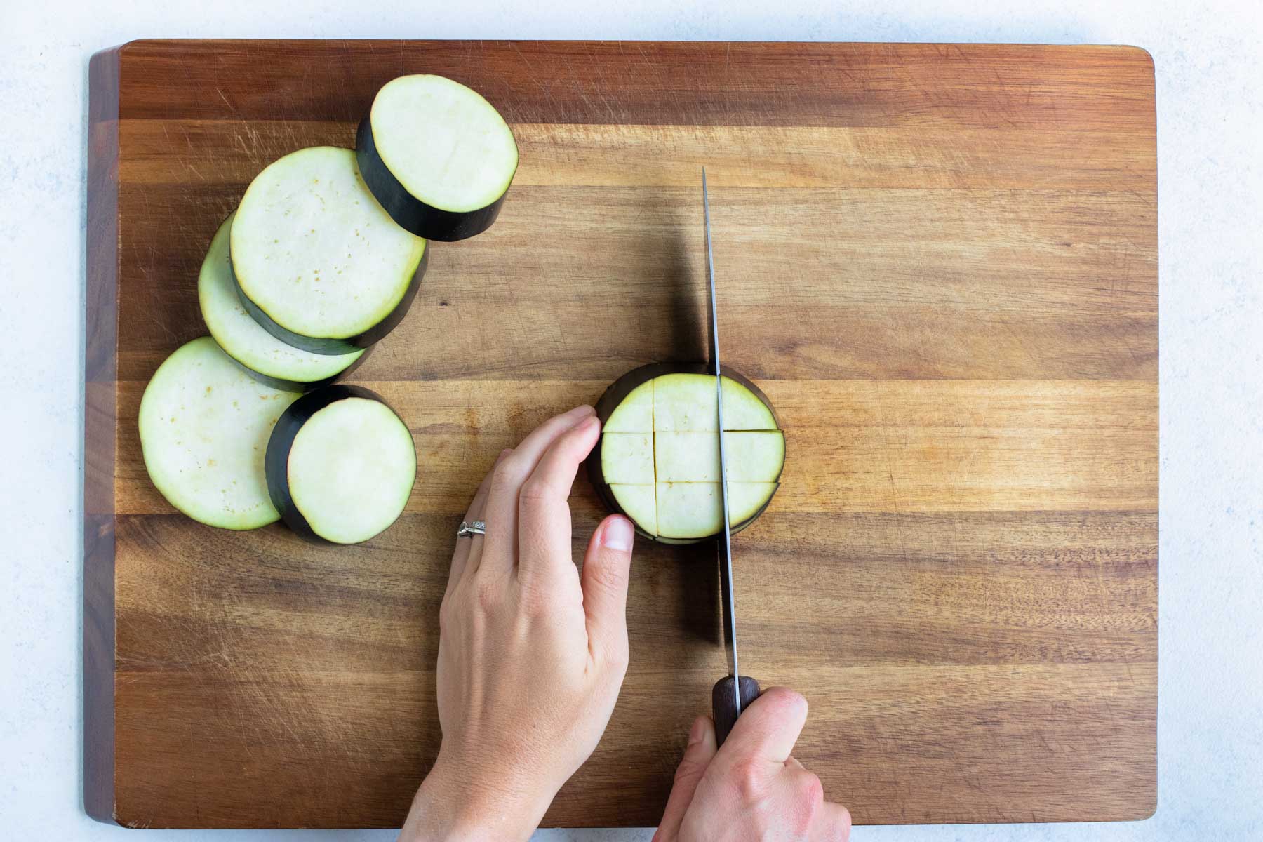 The eggplant is cubed on a cutting board.