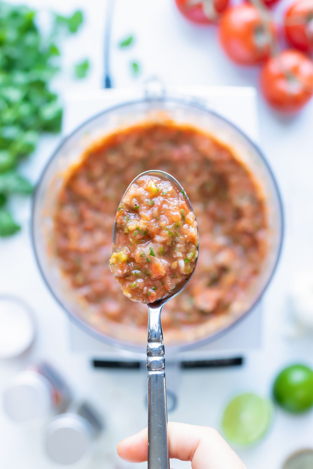 A metal spoon is used to lift healthy tomato salsa.