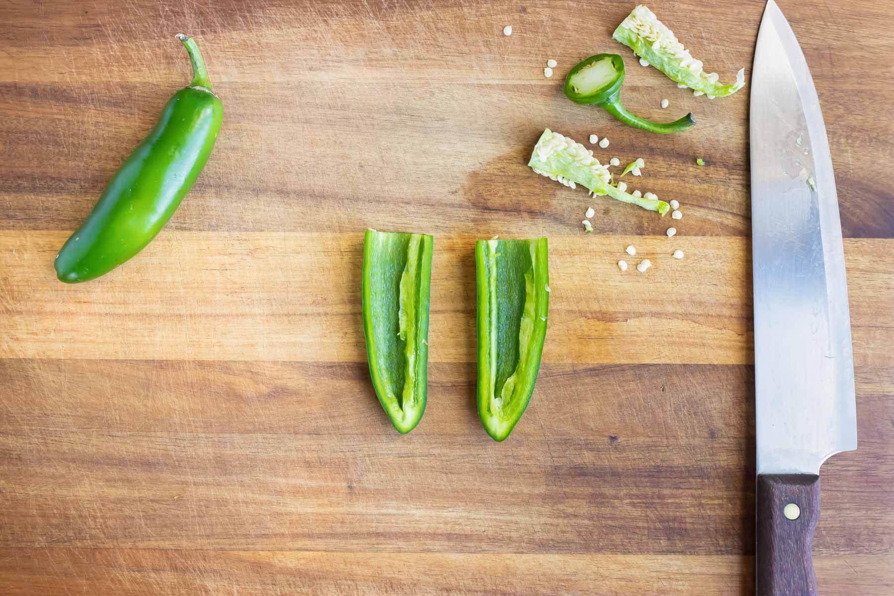 The jalapeño pepper is shown on a cutting board after being cut in half.