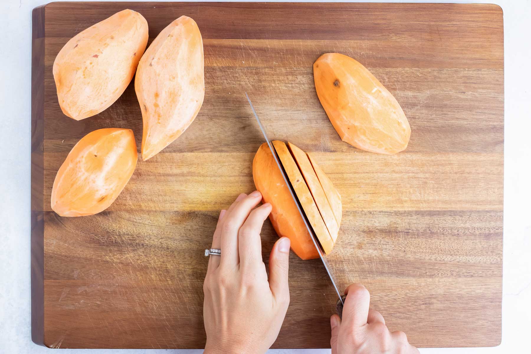A sweet potato is cut with a knife into slices.