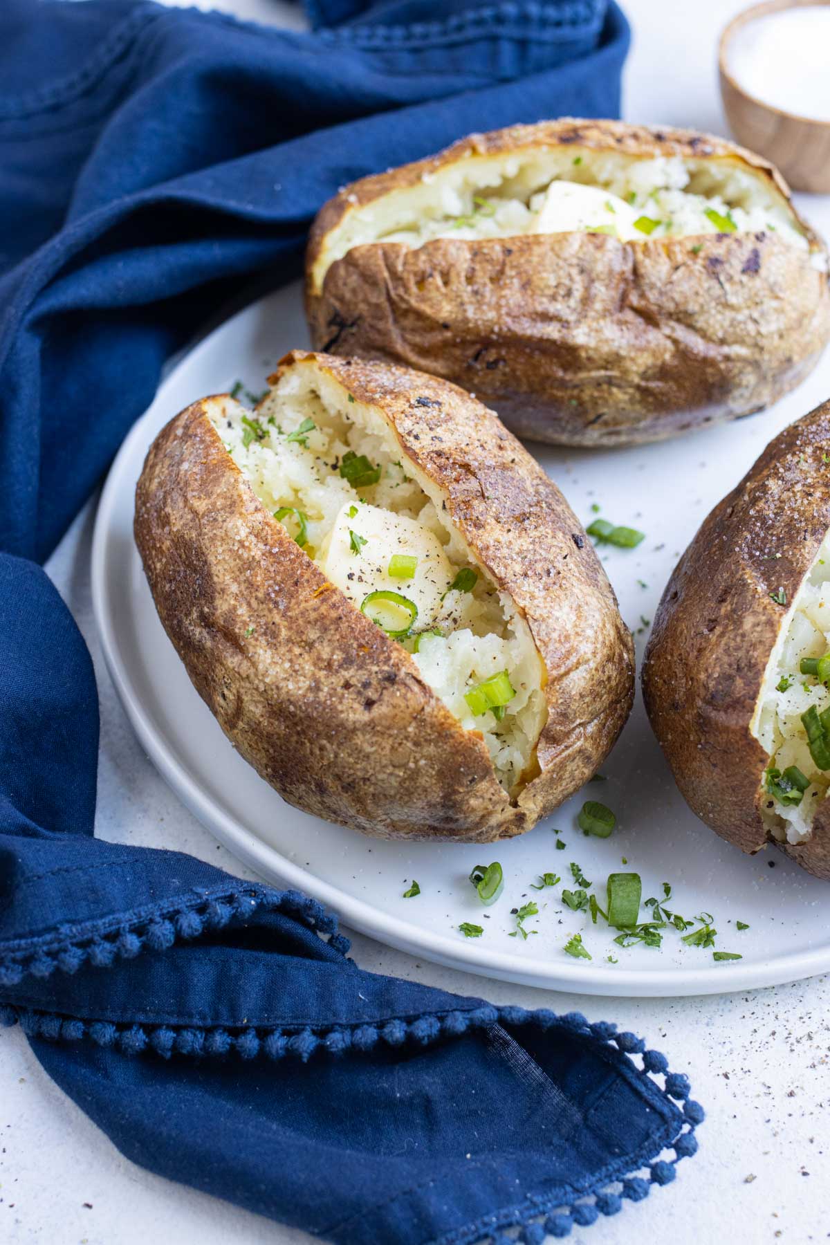 Baked potatoes are served on a white plate.