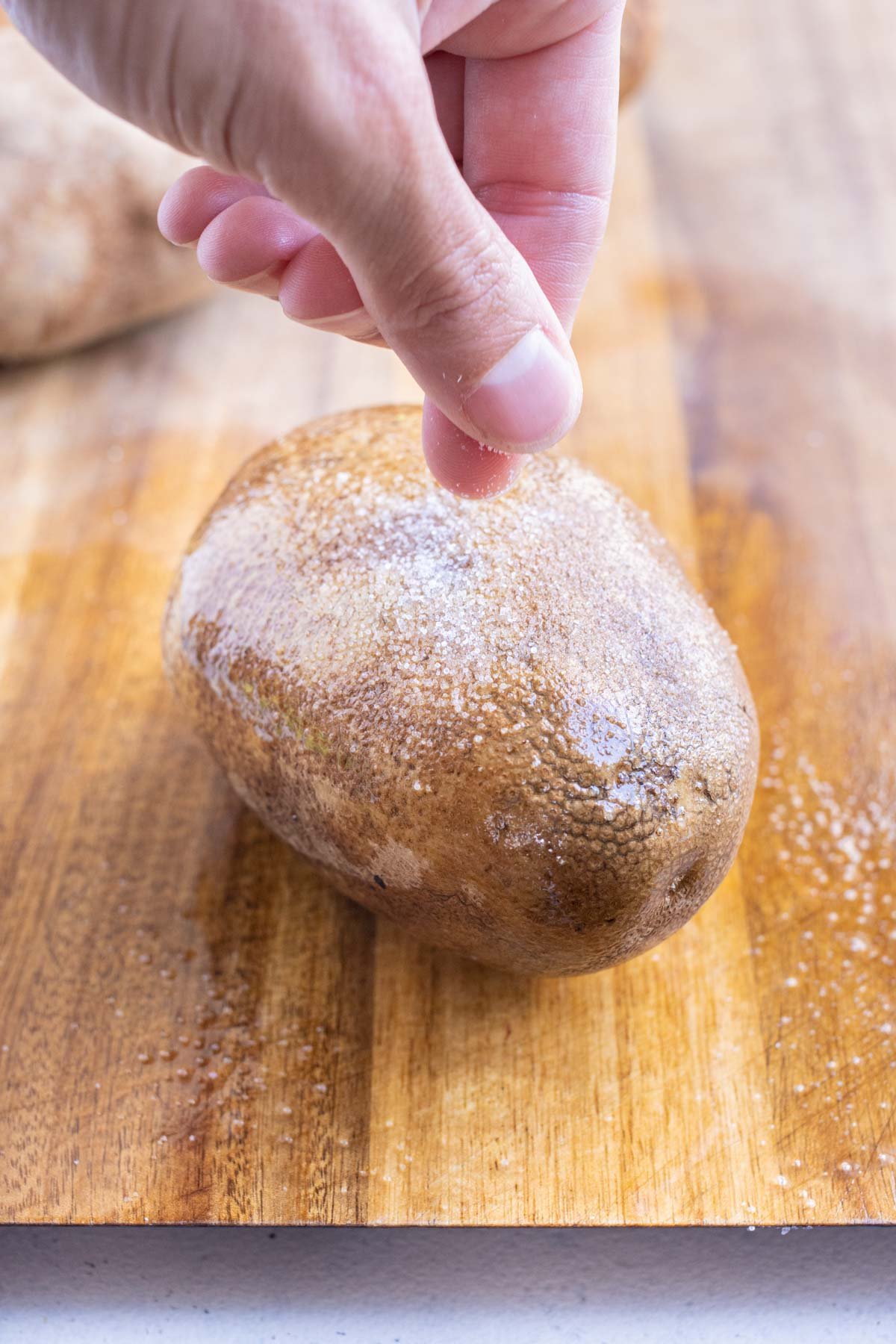 Salt is sprinkled on a potato with oil.