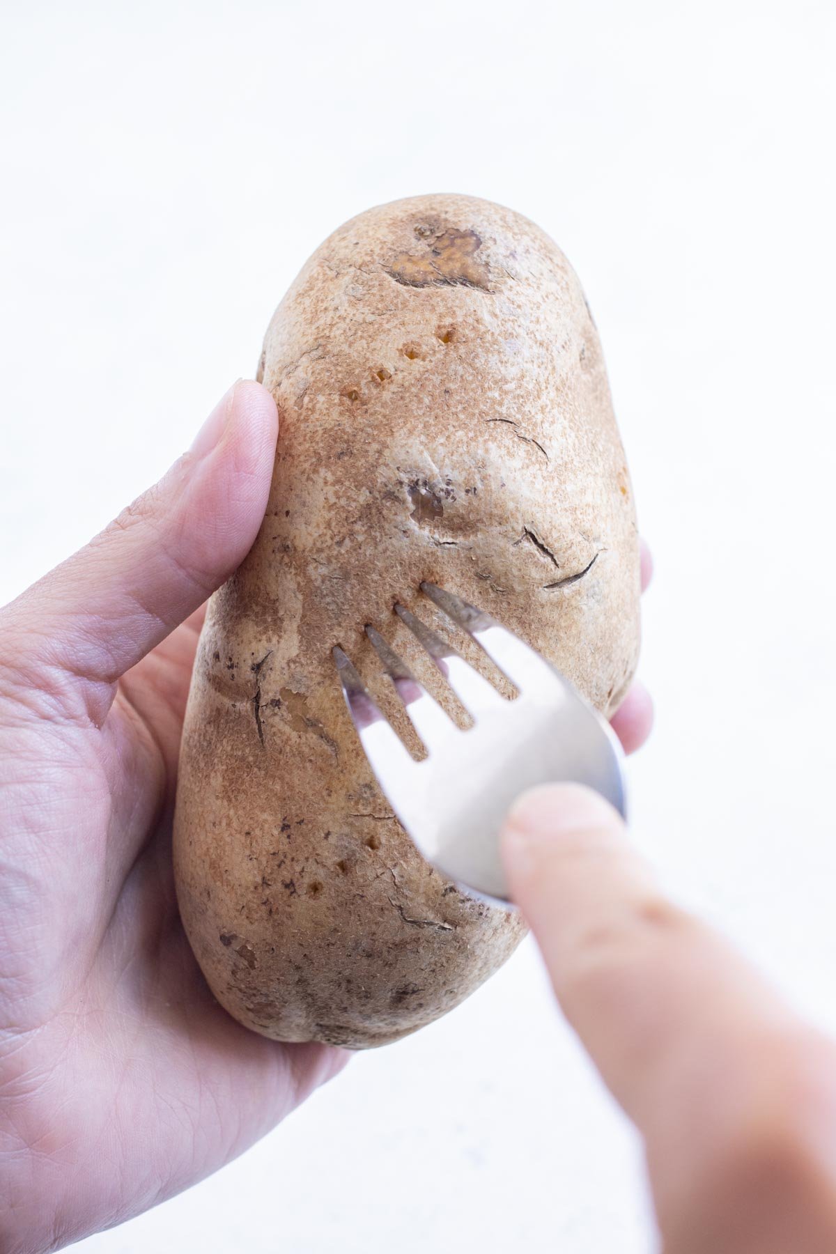 A fork pierces the potatoes to release steam.